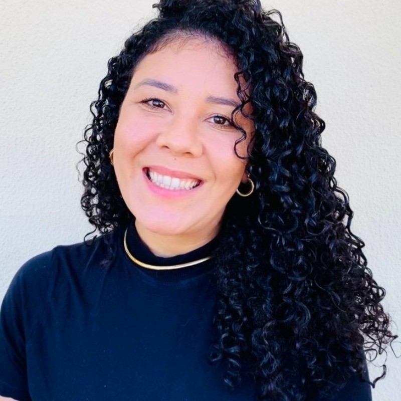 Foto de Thamires usando camisa preta, sorrindo com fundo branco